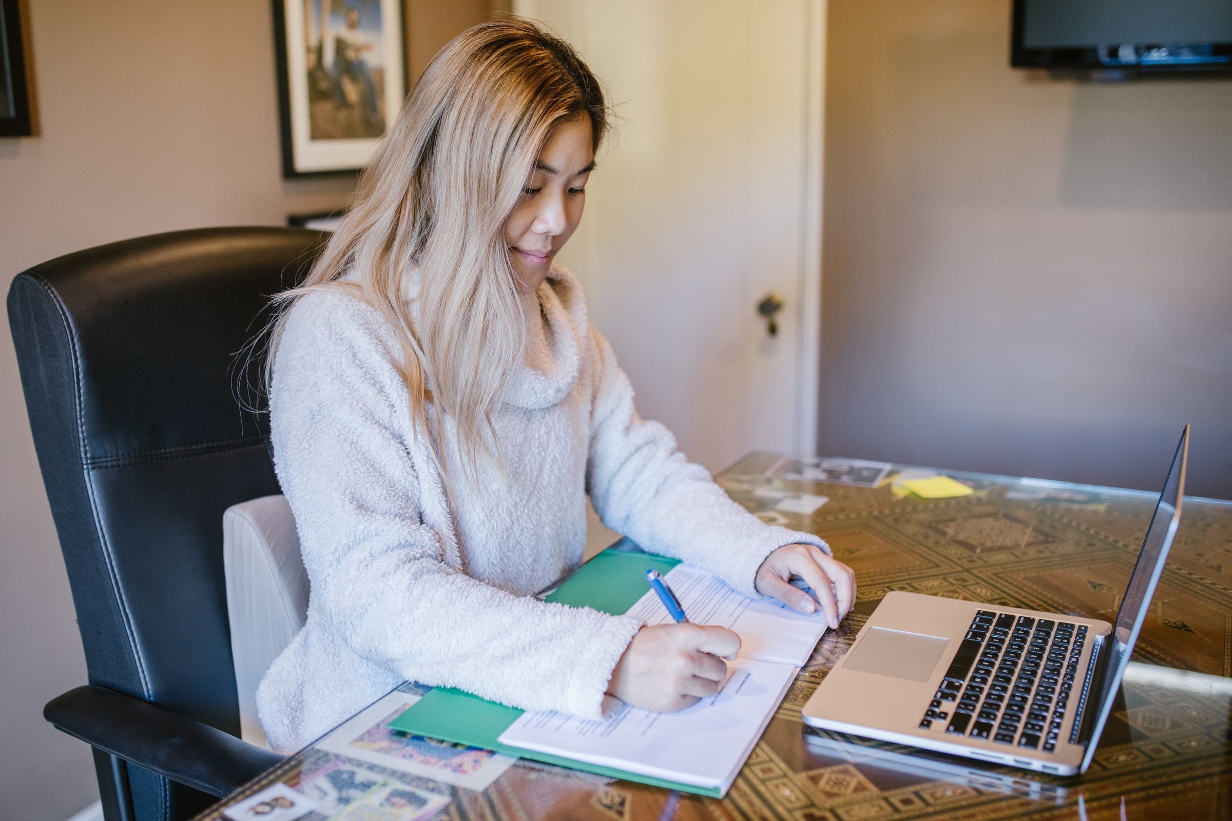 A director signing company change documents at a home-office desk, with a laptop and an envelope ready for the post.