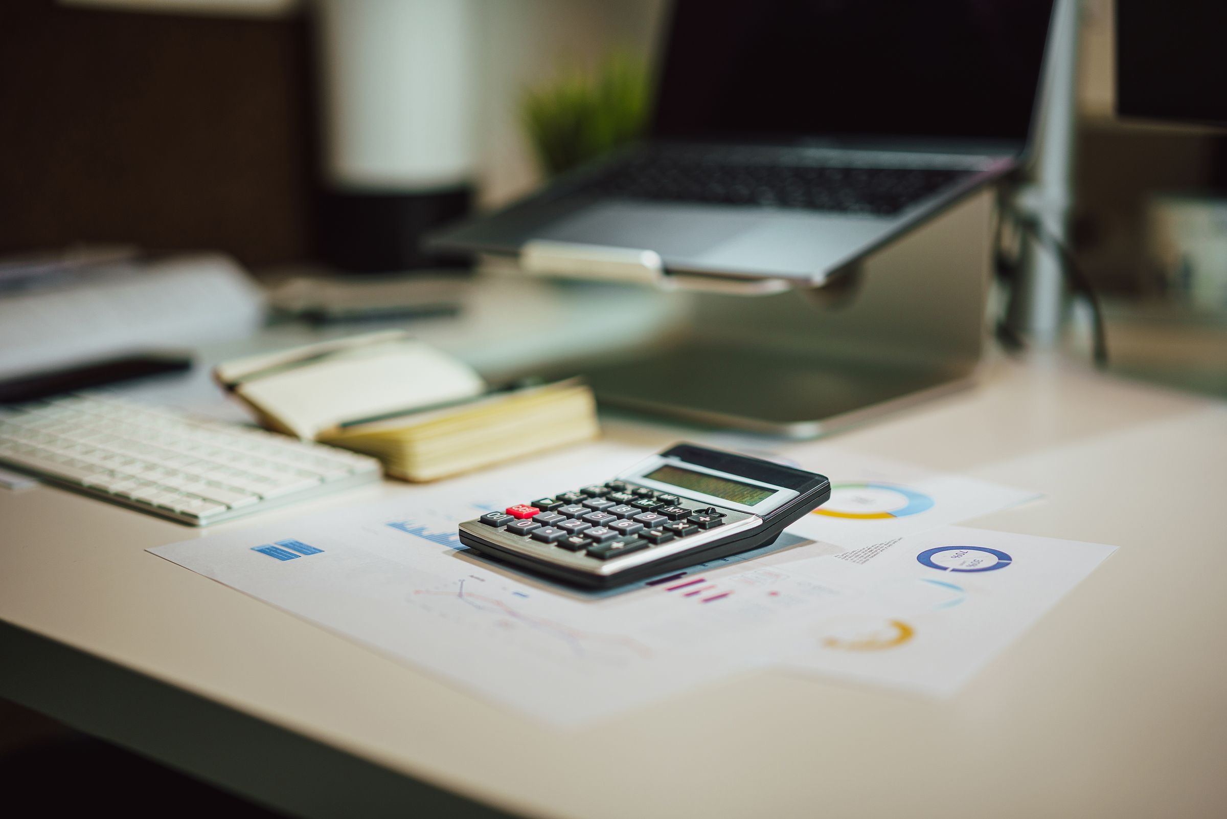 A founder reviewing the costs of forming a Dutch BV with documents, a calculator and a laptop.