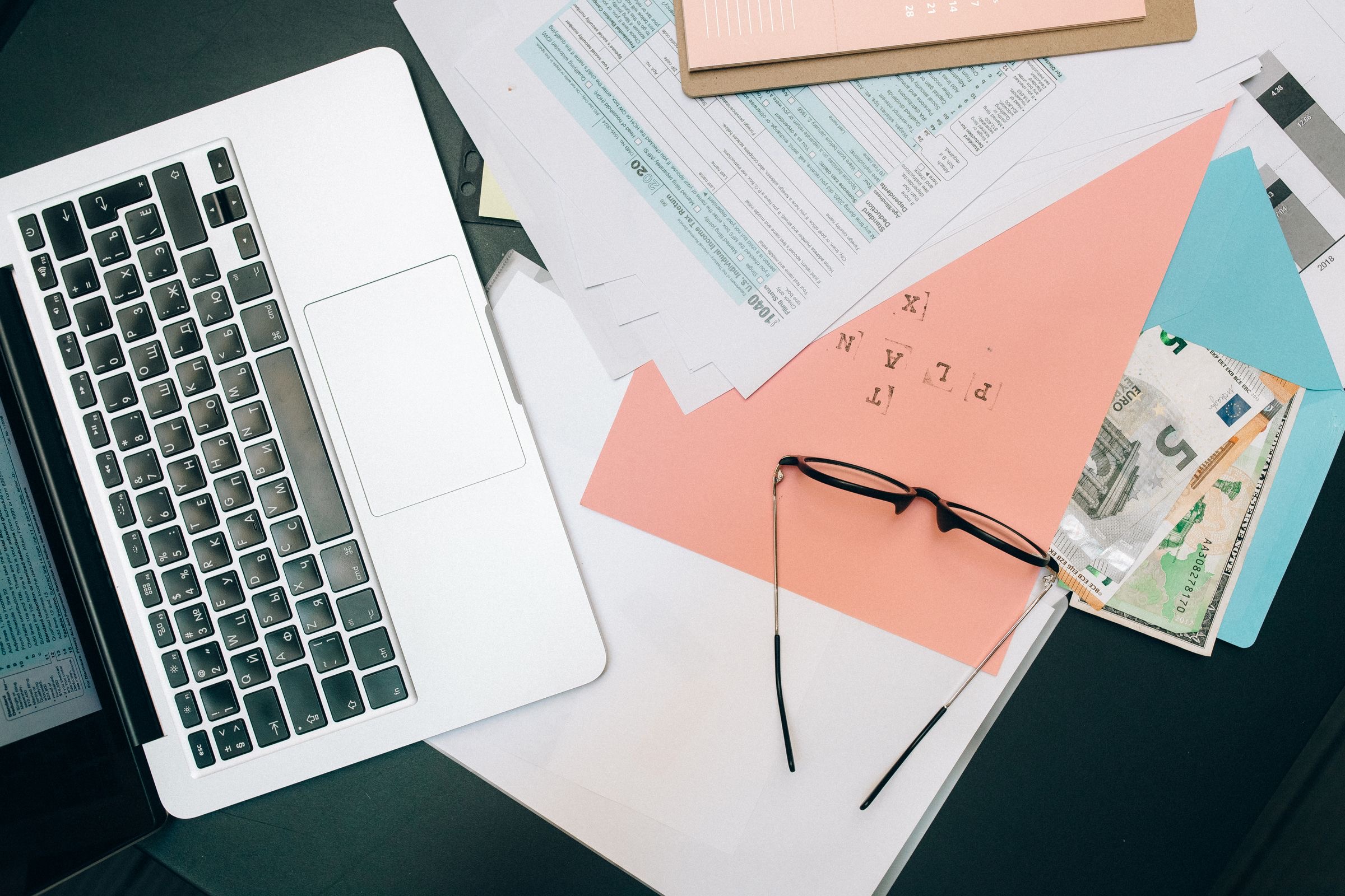 A company owner signing closing documents at a desk, with a laptop and an envelope ready for the post.
