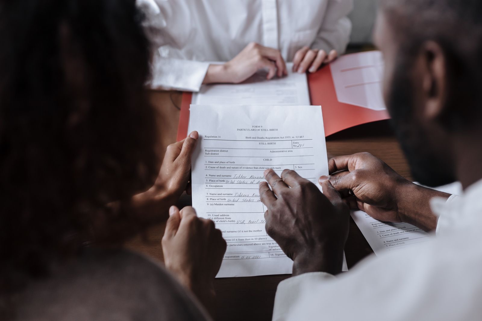 Several people signing one printed document at a table.