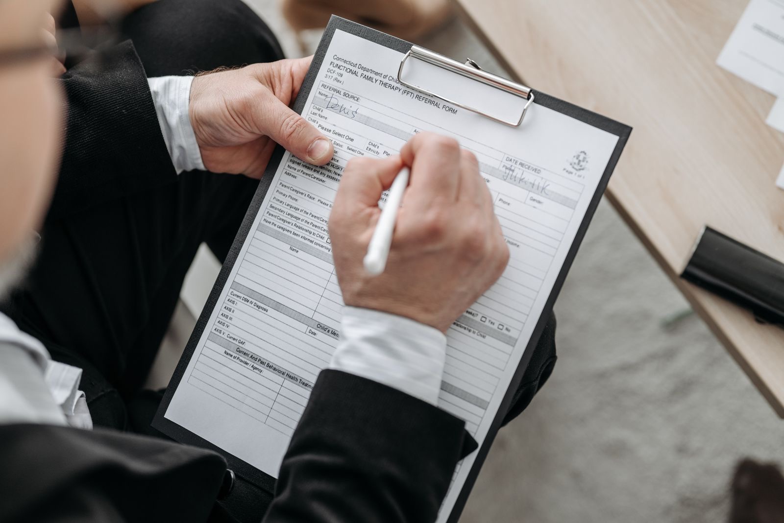 A close-up of a hand signing a document at a desk