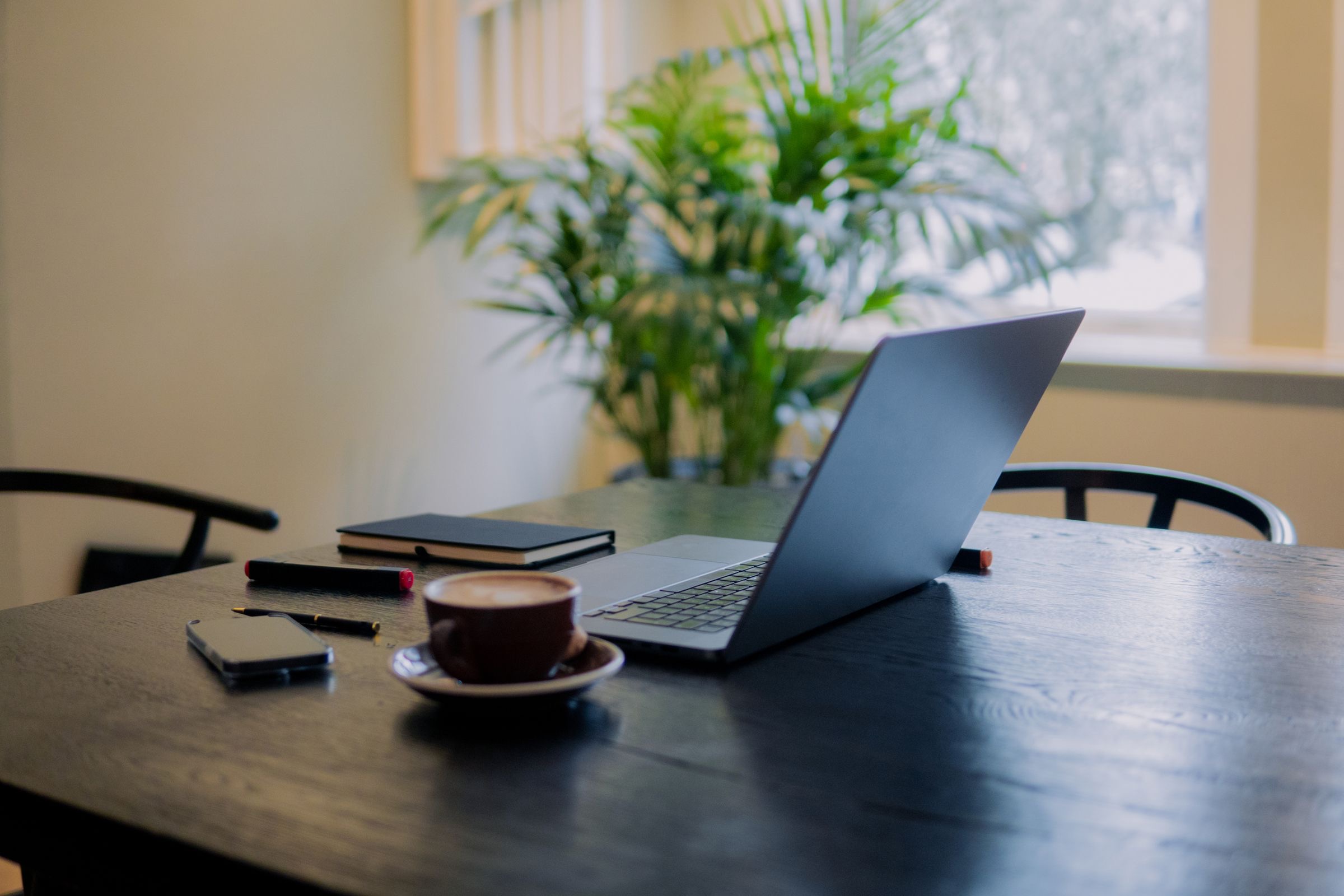 A desk with an open laptop by a tall canal-house window in Amsterdam