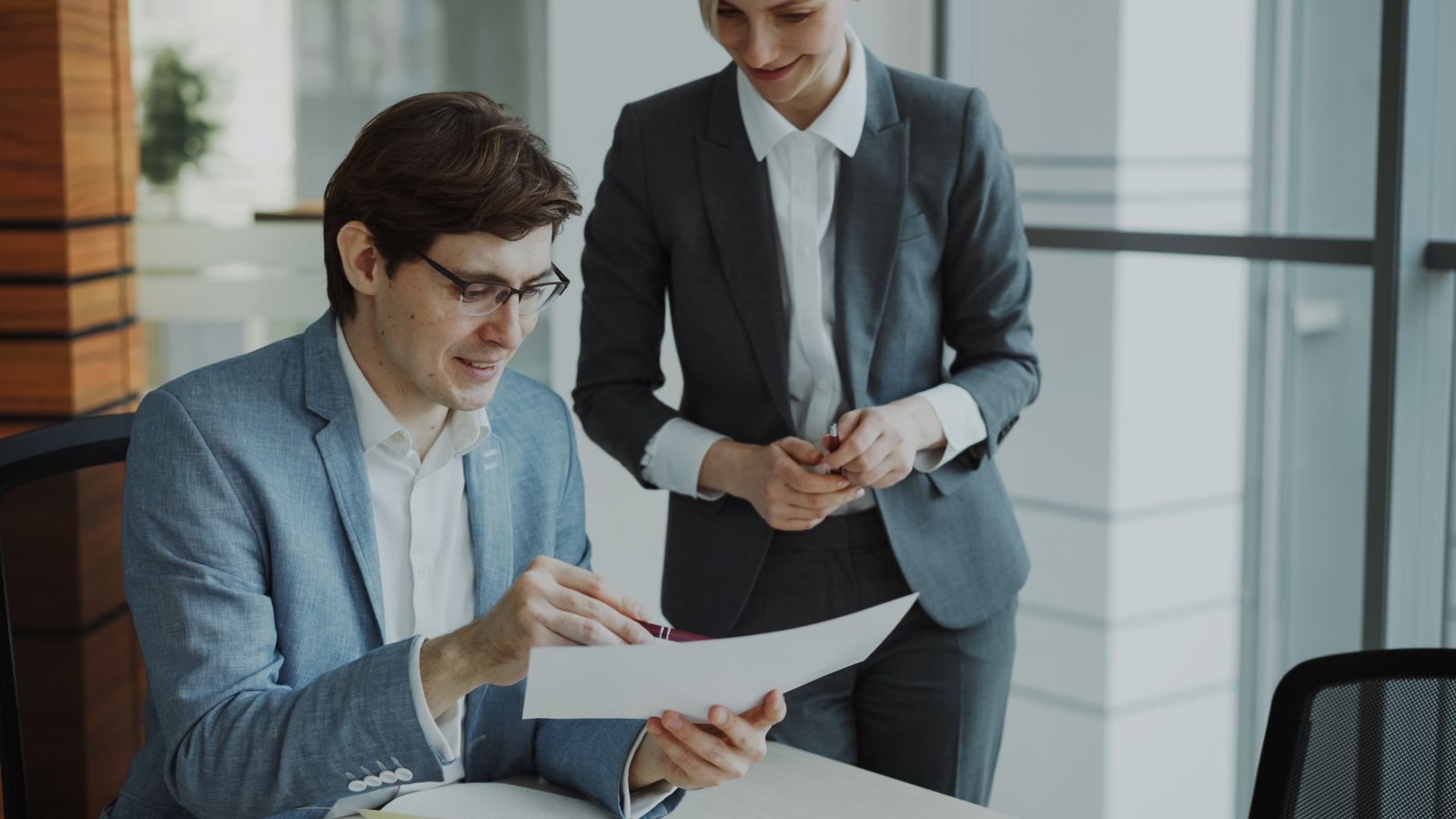 A consultant and a founder reviewing a business plan and permit documents at a desk.