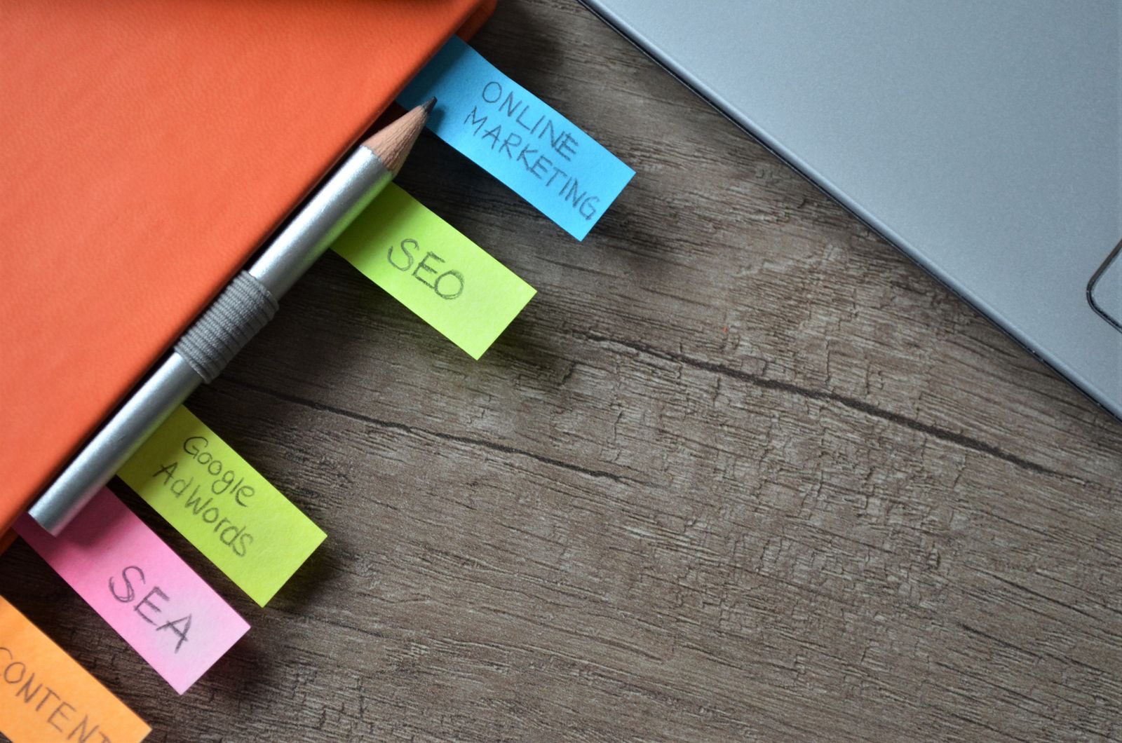 A laptop and handwritten notes on a desk during a trade mark name search.